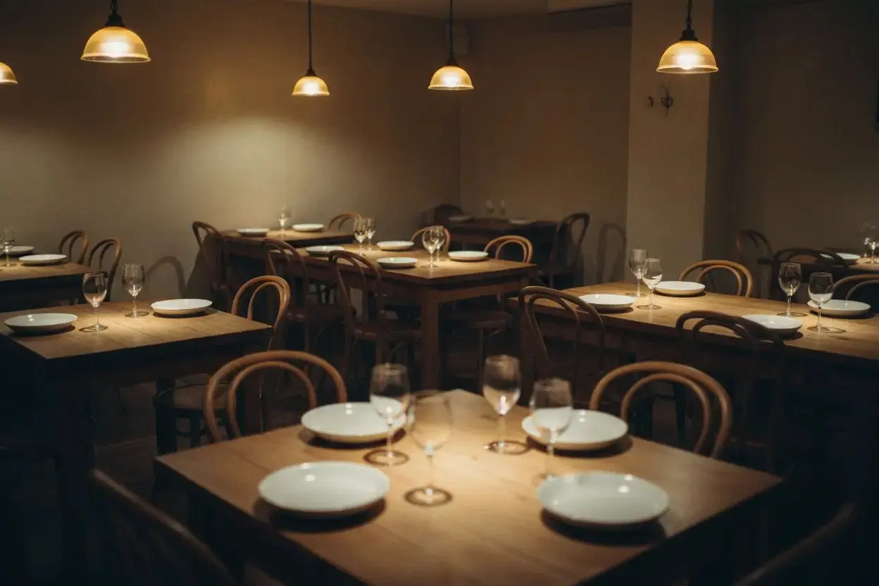 A warm, low-lit dining room with laid wooden tables